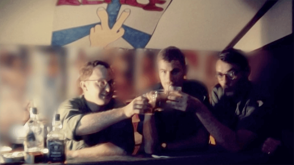 Three soldiers in a dimly lit room, drinking Jack Daniels and cheersing their shot glasses.