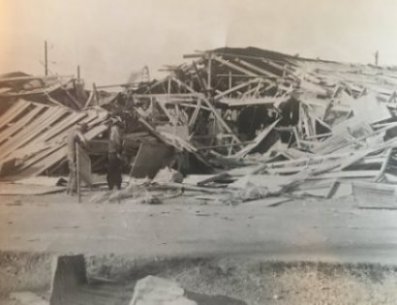 Two soldiers standing near debris of a building.