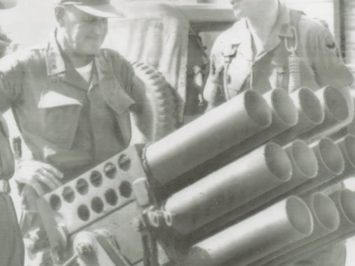 Two older soldiers inspecting a large piece of weaponry.