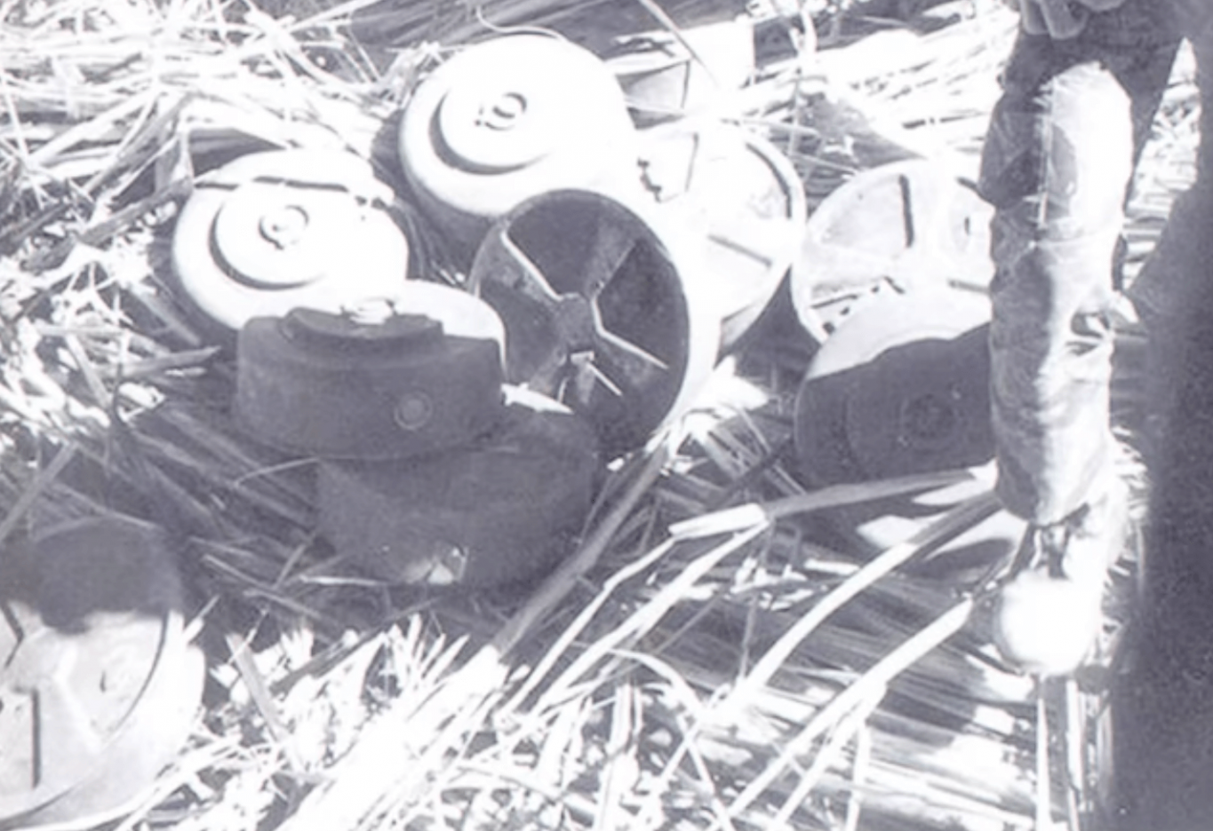 A pile of canisters on a hay-covered ground.