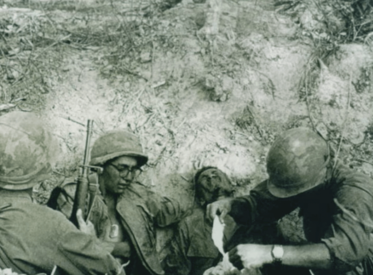 Three soldiers attending to one wounded soldier in the field.