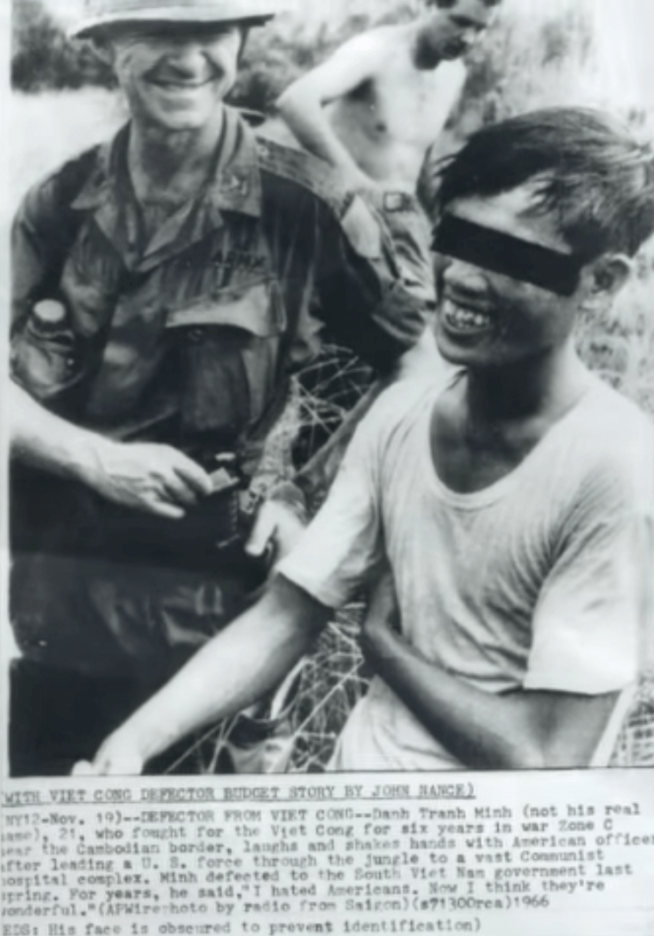 A US soldier withe an Asian solder, whose eyes are blacked out, perhaps to keep his identity secret. Headline reads "With Viet Cong Defector..."