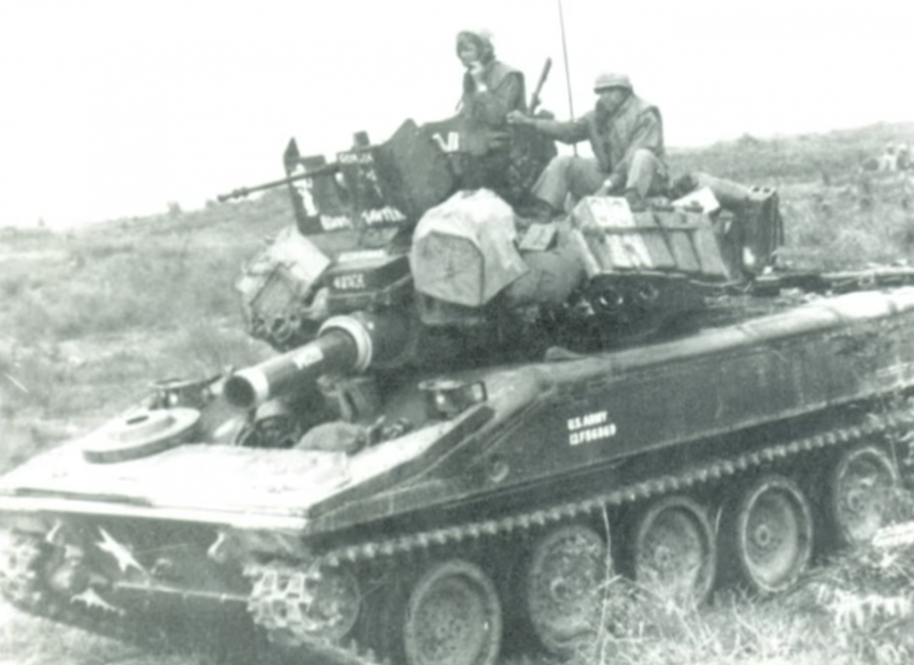 Two soldiers sitting atop a tank.