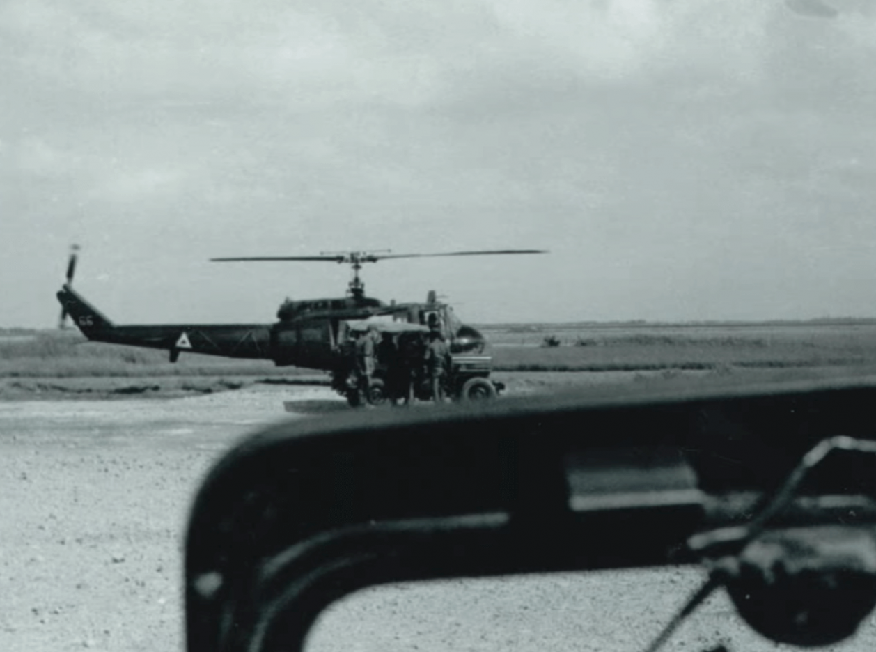 View from over the dash a Jeep: another Jeep parked aside a helicopter.