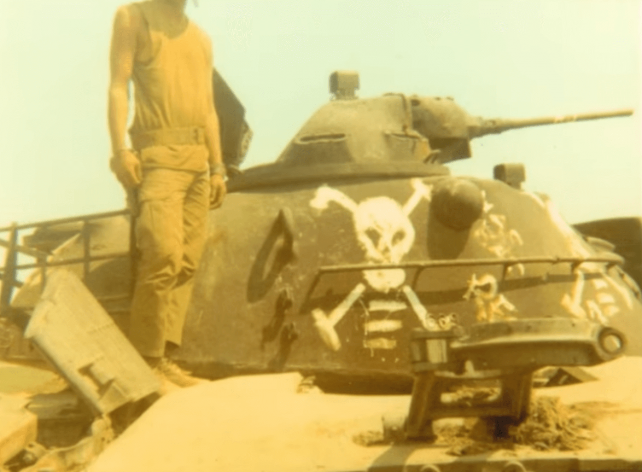 A gun mounted on top of a tank with a skull and cross bones painted on it.