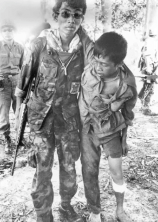 An Asian soldier assisting an injured child walk.