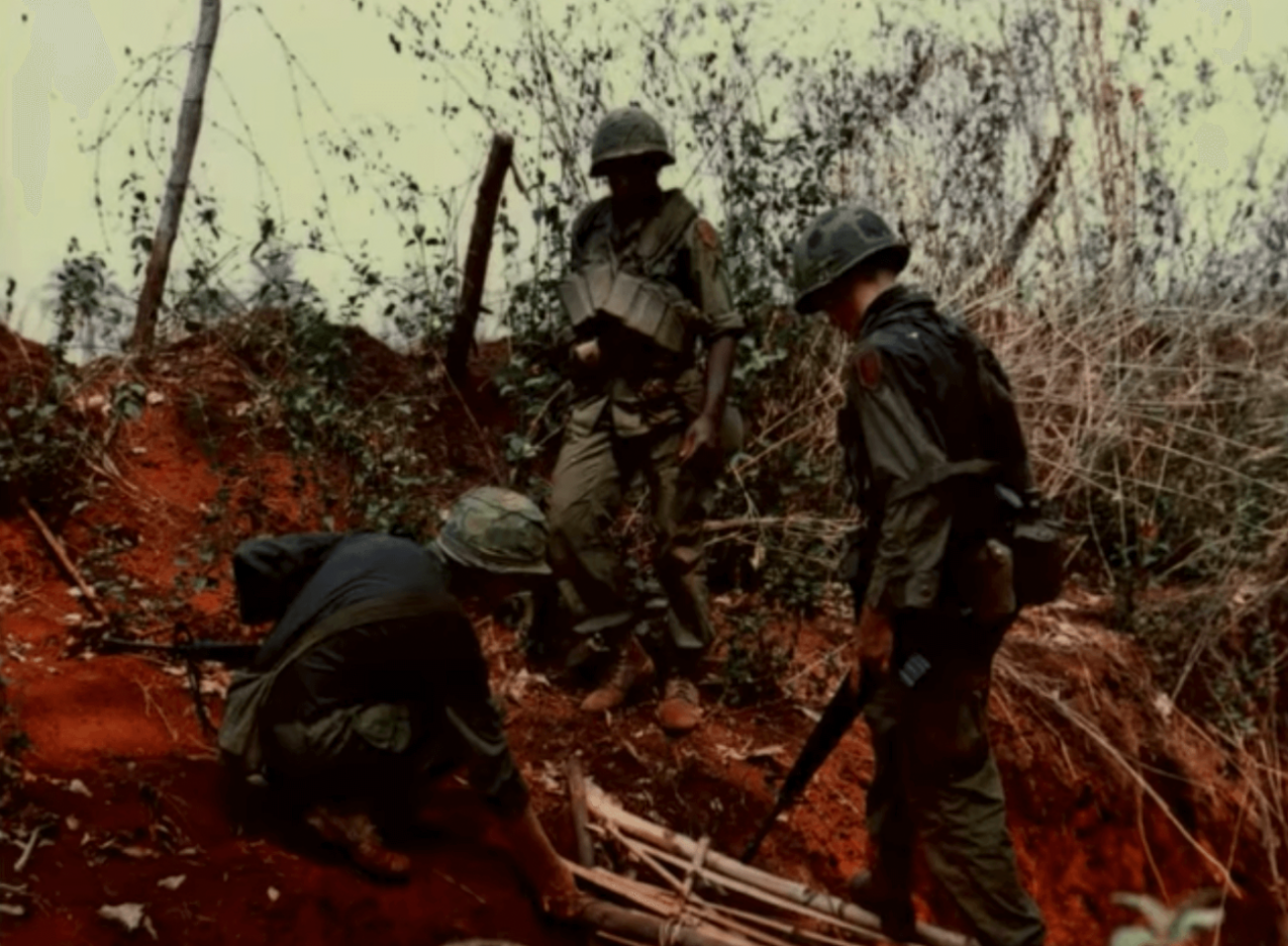 Three soldiers creating or deconstructing what looks to be a booby trap.