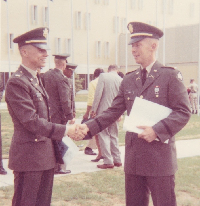 Two soldiers in uniform shaking hands.