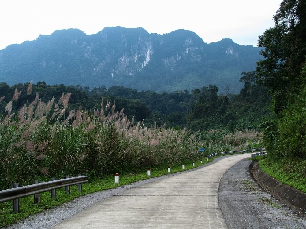 Contemporary photo of a road with mountains rising in the distance.