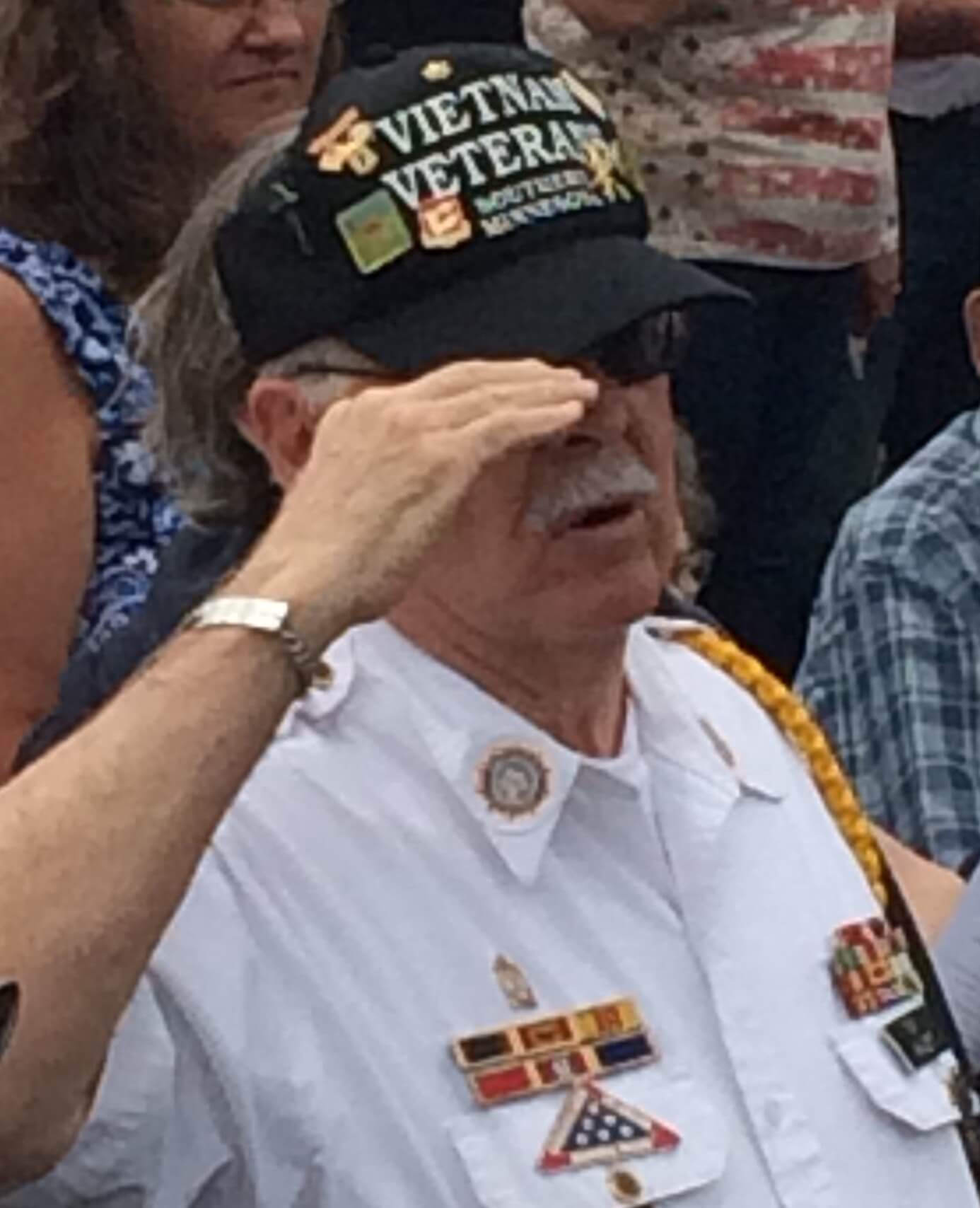 Vietnam veteran in a hat saluting.