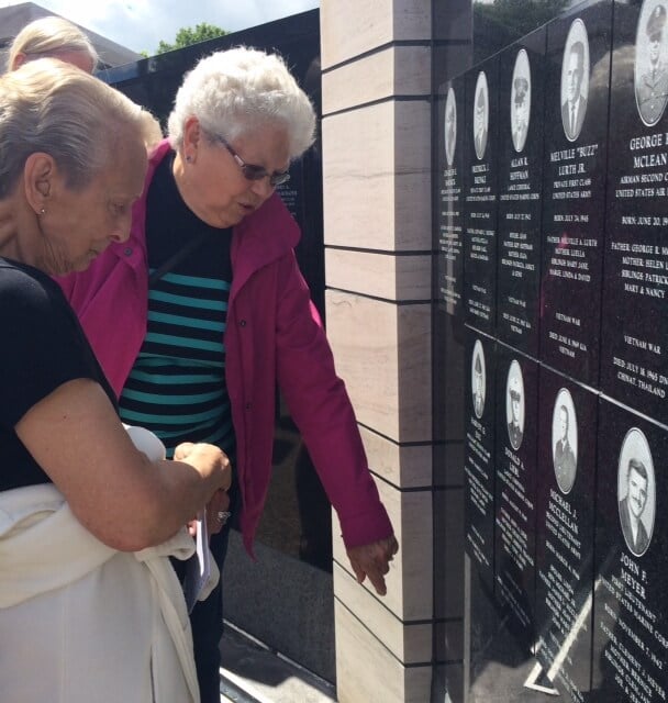 Two women looking at a war memorial.