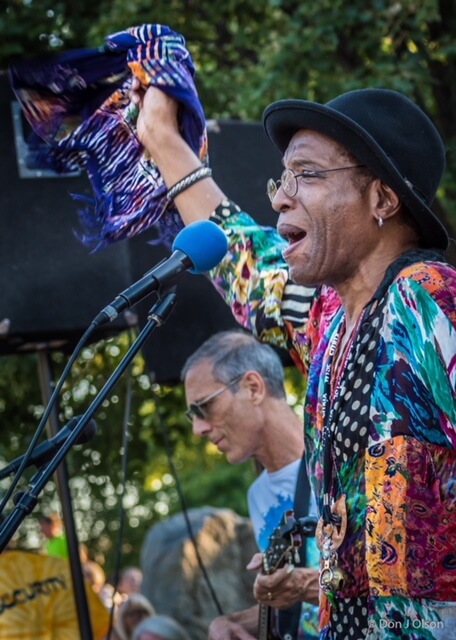 African American man singing at a concert at a park.