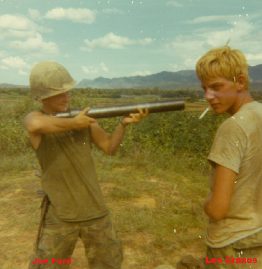 Two young US soldiers, one aiming a rocket (labeled as Joe Ford), one looking over his shoulder at the camera with a cigarette hanging out of his mouth (labeled Leo Granos).