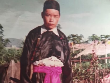 Hmong man dressed in pink sash and black suit.