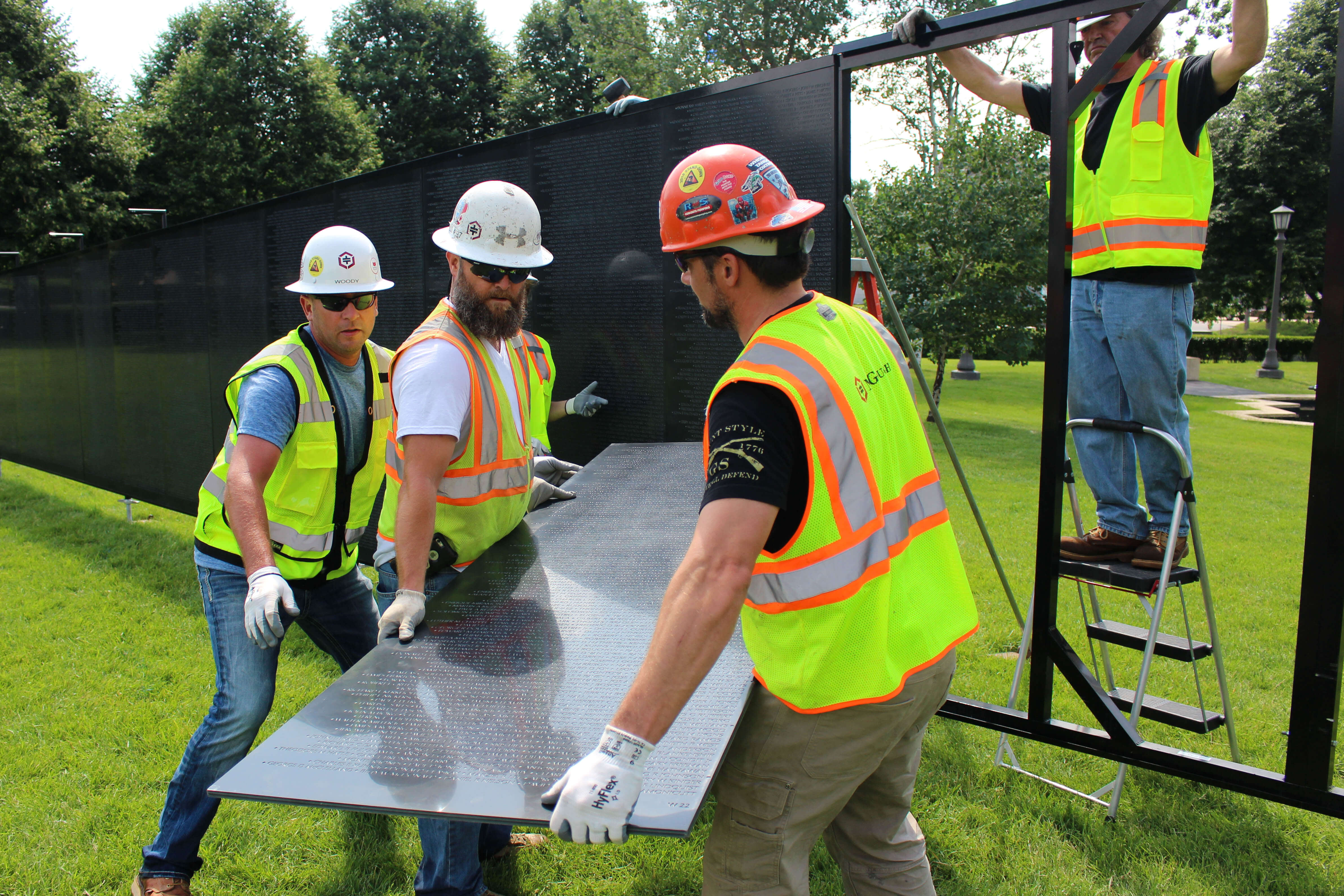Construction crew lifting a black panel.