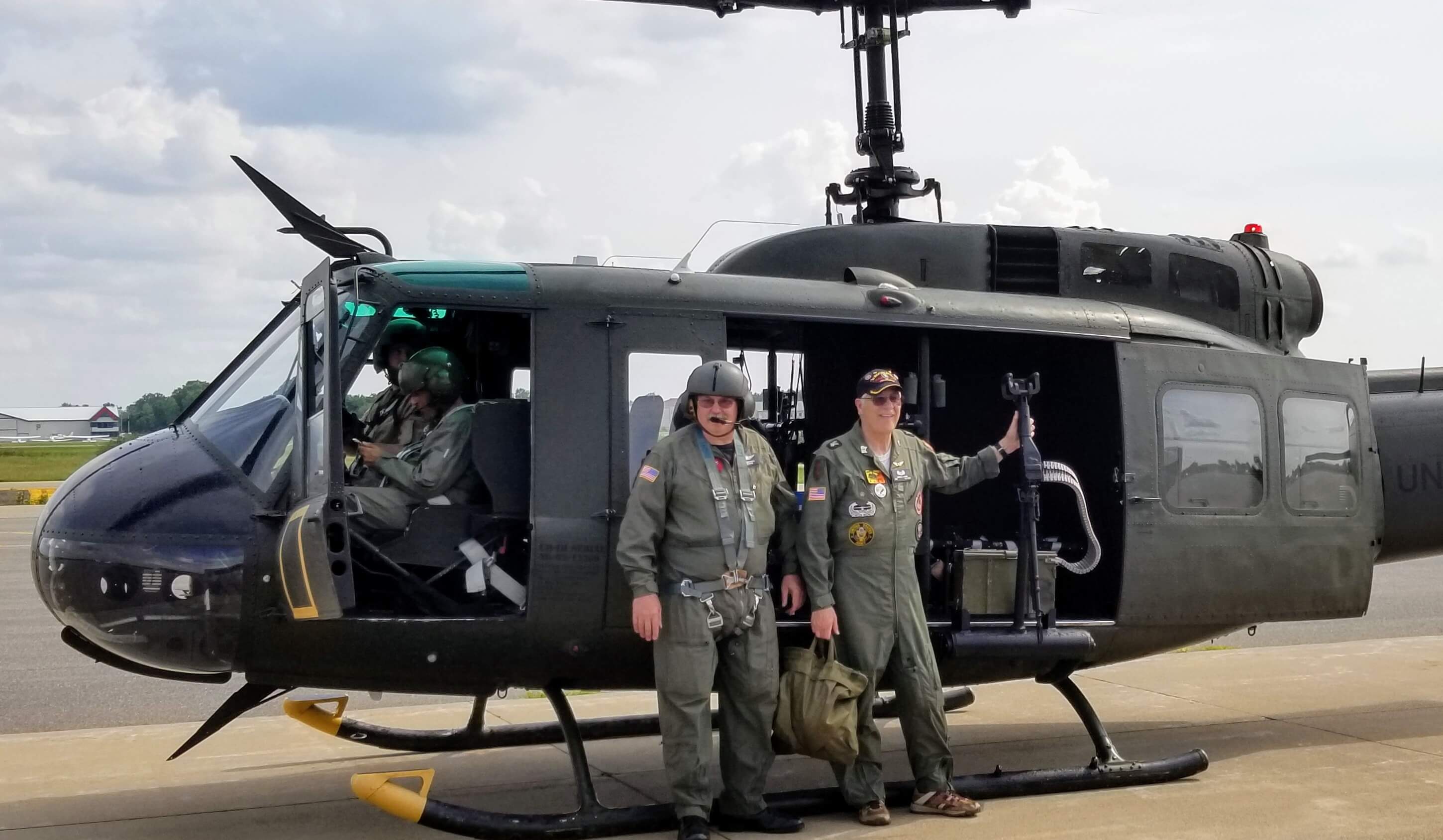 Men in front of a vintage Huey Helicopter