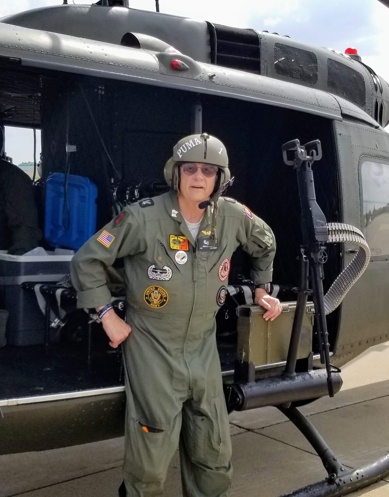 Man in flight suit in front of a Huey Helicopter